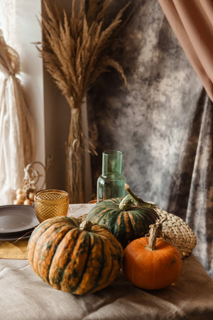 Autumn interior: a table covered with dishes, pumpkins, a relaxed composition of Japanese pampas grass. Interior in the photo Studio. Close - up of a decorated autumn tableの写真素材
