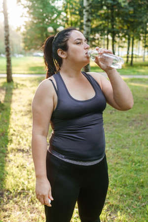A charming brunette woman plus-size body positive practices sports in natureの写真素材