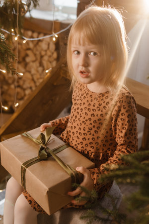 A little blonde girl is sitting on a wooden staircase in a Scandinavian interior decorated.の写真素材