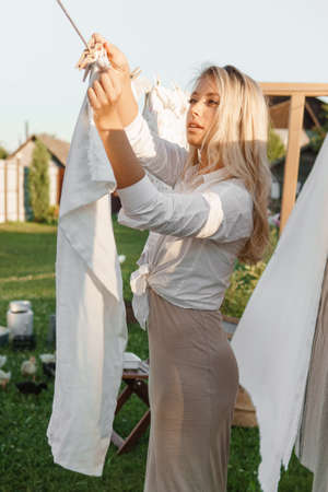 Laundry day. A woman hangs linen and towels on a tree in the courtyard of a village house.の写真素材