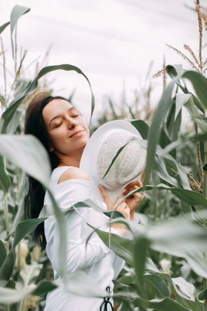 A brunette girl in a white dress in a cornfield. The concept of harvestingの写真素材