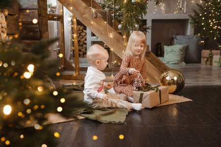 Little brother and sister play on Christmas eve in a beautiful house decorated for the New Year...