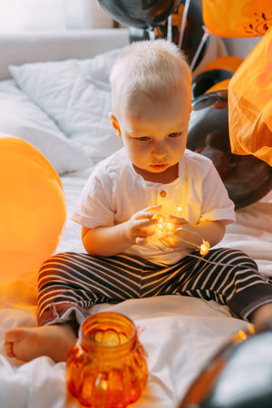 Childrens Halloween - a boy in a carnival costume with orange and black balloons at home. Ready to celebrate Halloweenの写真素材