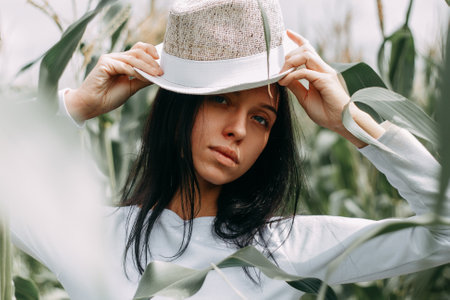 A brunette girl in a white dress in a cornfield. The concept of harvestingの写真素材