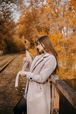 beautiful long-haired woman walks through the autumn streets. Railway, autumn, woman in a coat.の写真素材