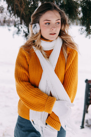 Teen blonde in a yellow sweater outside in winter. A teenage girl on a walk in winter clothes in a...