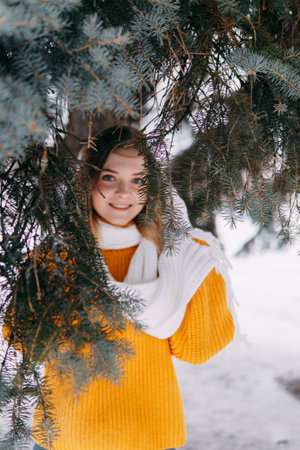Teen blonde in a yellow sweater outside in winter. A teenage girl on a walk in winter clothes in a snowy forestの写真素材