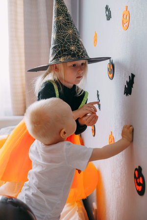 Childrens Halloween - a boy and a girl in carnival costumes with orange and black balloons at home. Ready to celebrate Halloweenの写真素材