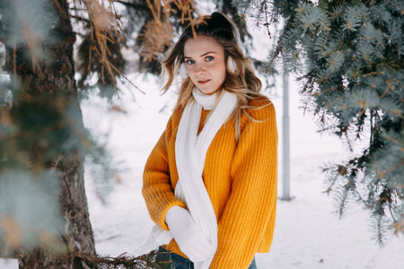 Teen blonde in a yellow sweater outside in winter. A teenage girl on a walk in winter clothes in a snowy forestの写真素材