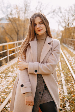 beautiful long-haired woman walks through the autumn streets. Railway, autumn, woman in a coat.の写真素材