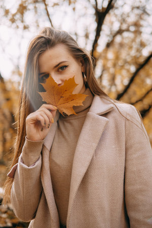 beautiful long-haired woman walks through the autumn streets. Railway, autumn, woman in a coat.の写真素材