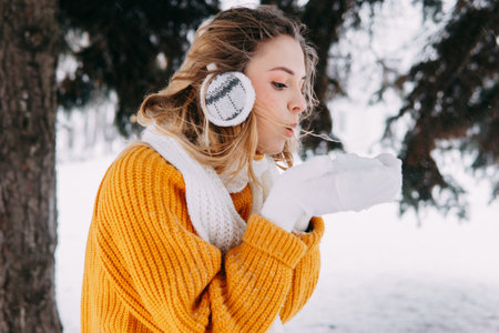 Teen blonde in a yellow sweater outside in winter. A teenage girl on a walk in winter clothes in a snowy forestの写真素材