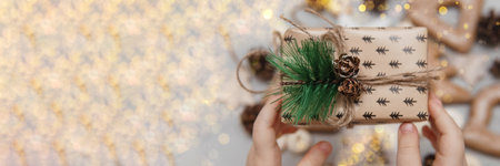 Childrens hands hold a small Christmas gift. Concept of Christmas sweets, toys, garlands and bokeh. Decor for New Year holidays.の写真素材