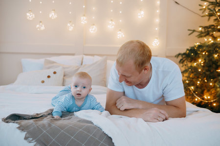 Dad and son at home on the bed. The concept of family relations and the atmosphere of Christmasの写真素材