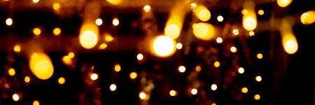 Blurry garland lights on a dark background. Festive Christmas and New Year background. Soft focus