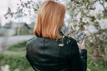 A red-haired teenage girl listens to music in headphones, configured via the phone. The time of...