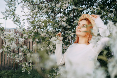 Portrait of a woman in a straw hat in a cherry blossom. Free outdoor recreation, spring blooming garden.の写真素材