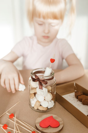 A little girl blogger makes a sweet Valentines Day gift with her own hands. A gift for the holiday, a video blog entry.の写真素材