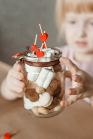 A little girl blogger makes a sweet Valentines Day gift with her own hands. A gift for the holiday, a video blog entry.の写真素材