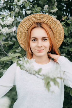 Portrait of a woman in a straw hat in a cherry blossom. Free outdoor recreation, spring blooming...