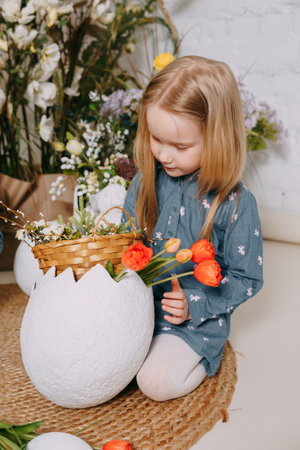 Two girls in a beautiful Easter photo zone with flowers, eggs, chickens and Easter bunnies. Happy...