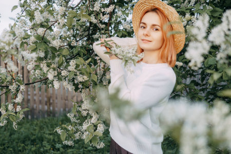 Portrait of a woman in a straw hat in a cherry blossom. Free outdoor recreation, spring blooming garden.の写真素材