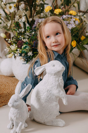 Two girls in a beautiful Easter photo zone with flowers, eggs, chickens and Easter bunnies. Happy...