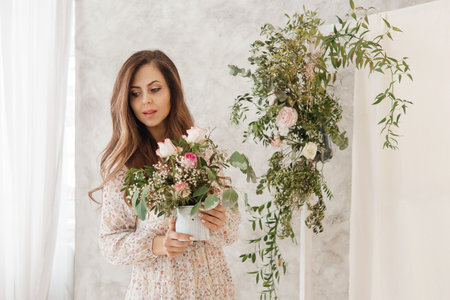 A brown-haired woman with long hair is having breakfast in a beautiful floral location. Spring portrait.の写真素材