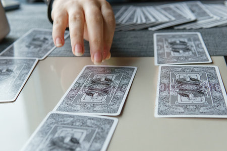 TVER, RUSSIA - FEBRUARY 11, 2023. Tarot cards, Tarot card divination, esoteric background. A woman makes a layout on the cards at the table. Divination, predictions on tarot cards.のeditorial素材