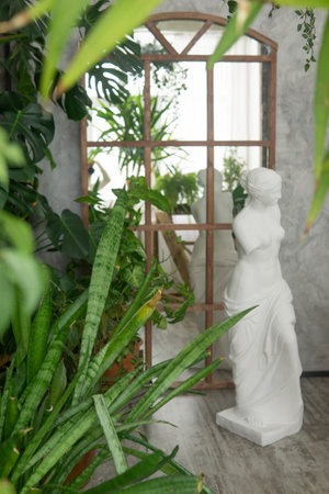 A fragment of the interior with a variety of indoor plants and plaster sculptures. Urban jungle concept. Biophilia design.の写真素材