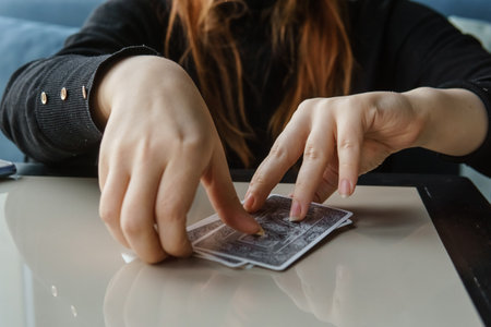TVER, RUSSIA - FEBRUARY 11, 2023. Tarot cards, Tarot card divination, esoteric background. A woman makes a layout on the cards at the table. Divination, predictions on tarot cards.のeditorial素材