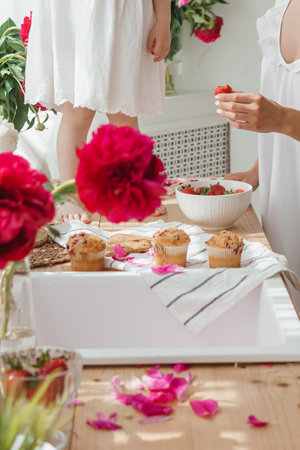 The kitchen countertop is decorated with peonies. Pink peonies and sweet cupcakes on wooden countertopの写真素材