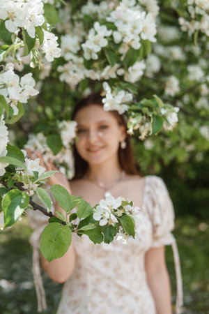 An attractive long-haired woman walks in the spring in the park of blooming apple trees.の写真素材