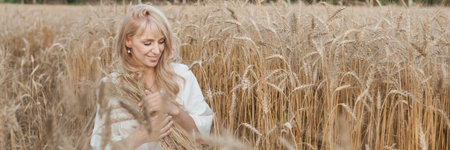 A blonde woman in a long white dress walks in a wheat field. The concept of a wedding and walking in nature.の写真素材