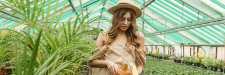 A beautiful young woman takes care of plants in a greenhouse. The concept of gardening and an eco-friendly lifestyle.の写真素材