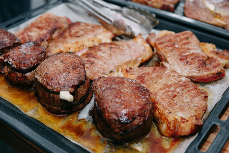 cooking steaks in a pan. cooking beef at the culinary master class. the hands of the chef in black...