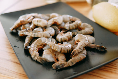 Peeled tiger prawns on a black plate. Culinary master class on cooking seafood. Close-up, selective focus. Home cooking.の写真素材
