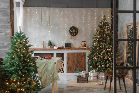 Home New Years interior. Christmas tree with gifts, decorated with garlands in the kitchen. Cozy atmosphere of a home holiday, loft design of the room, Scandinavian style.の写真素材