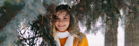 Teen blonde in a yellow sweater outside in winter. A teenage girl on a walk in winter clothes in a snowy forestの写真素材