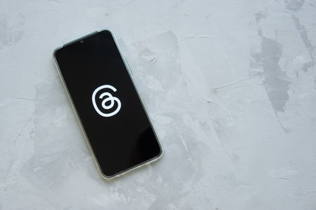 Tver, Russia - July 15, 2023, threads logo on the smartphone screen, on a gray background. The threads icon. The logo of the current application. Threads social network.のeditorial素材