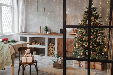 Home New Years interior. Christmas tree with gifts, decorated with garlands in the kitchen. Cozy atmosphere of a home holiday, loft design of the room, Scandinavian style.の写真素材