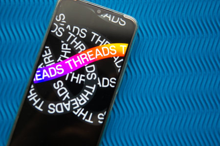 Tver, Russia - July 15, 2023, threads logo on the smartphone screen, on a blue background. The threads icon. The logo of the current application. Threads social network.のeditorial素材