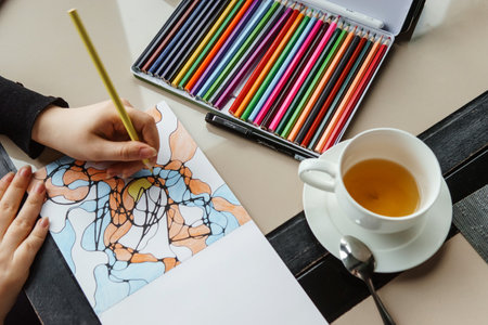 TVER, RUSSIA - FEBRUARY 11, 2023: a young woman draws neurography at a table at a psychological session, a neurographic resunok with a pencil to remove oranicheniy, art therapy.のeditorial素材