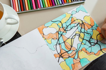 TVER, RUSSIA - FEBRUARY 11, 2023: a young woman draws neurography at a table at a psychological session, a neurographic resunok with a pencil to remove oranicheniy, art therapy.のeditorial素材