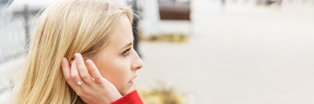 A young blonde woman walks around the autumn city in a red coat. The concept of urban style and lifestyleの写真素材