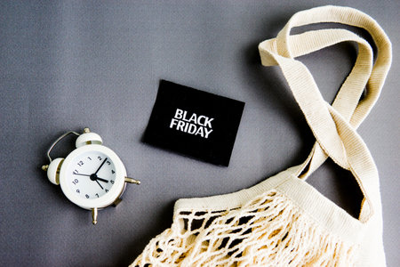 white alarm clock, string bag and black square inscription-Black Friday on a gray background. The topic of sales.の写真素材