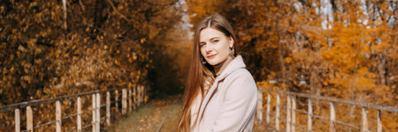 beautiful long-haired woman walks through the autumn streets. Railway, autumn, woman in a coat.の写真素材