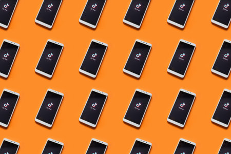 Tver, Russia - February 12, 2020 Tik tok logo on smartphone screen on orange background. Tik Tok icon. tik tok application. Tiktok Social media network.のeditorial素材