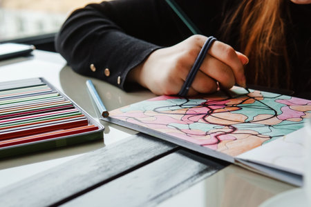 TVER, RUSSIA - FEBRUARY 11, 2023: a young woman draws neurography at a table at a psychological session, a neurographic resunok with a pencil to remove oranicheniy, art therapyのeditorial素材