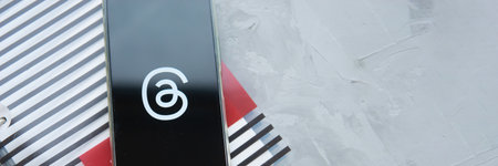 Tver, Russia - July 15, 2023, threads logo on the smartphone screen, on a gray background. The threads icon. The logo of the current application. Threads social network.のeditorial素材